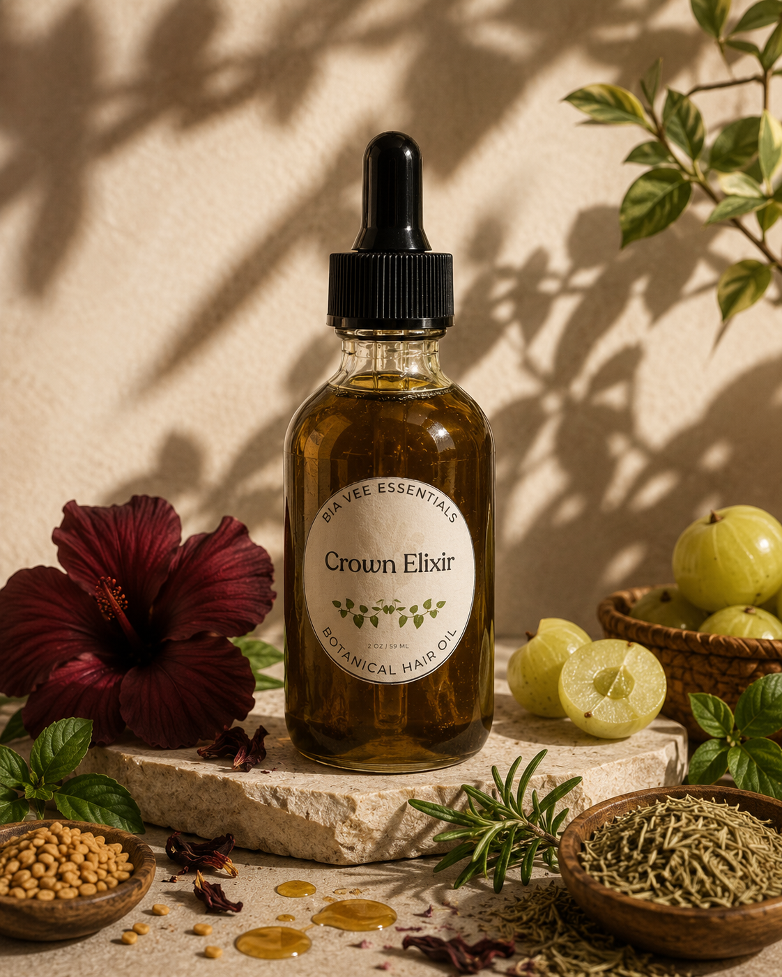 A bottle of Crown Elixir Botanical Hair Oil by Bia Vee Essentials, displayed on a stone slab with natural shadows. The amber glass bottle contains a golden oil and is surrounded by botanical ingredients including a hibiscus flower, gooseberries (amla), rosemary,  fenugreek seeds, and herbs.